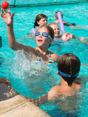 Kinder spielen Wasserspiele im Pool