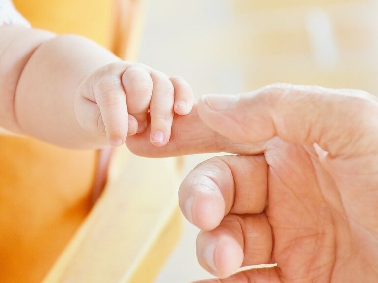 Säugling hält Finger von Elternteil
