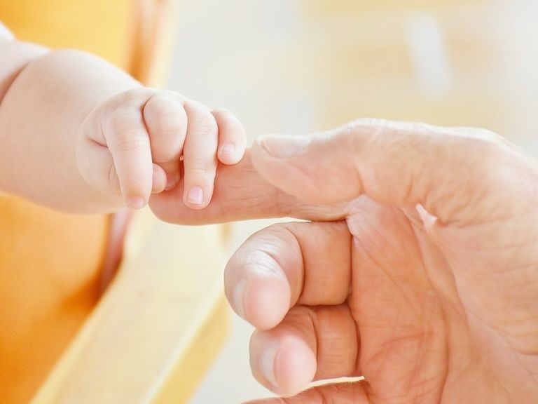 Säugling hält Finger von Elternteil