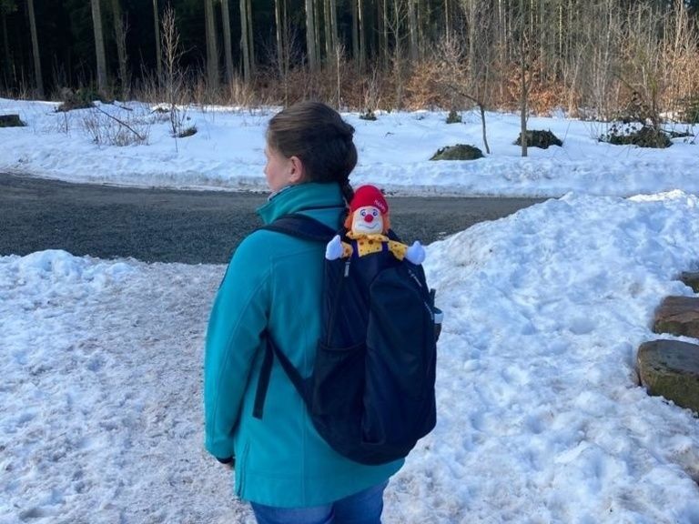 Wandern im Schnee mit Puppe Happy im Rucksack