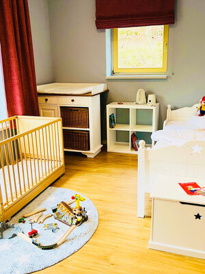 Helles Kinderzimmer mit Einzelbett und Gitterbett und Spielzeug