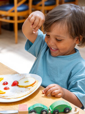 Kind genießt eine Mahlzeit mit Obst und Pfannkuchen - Kids All-Inclusive
