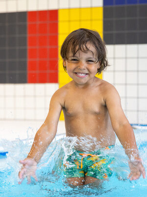Lachendes Kind plantscht im Pool im Family Club Harz