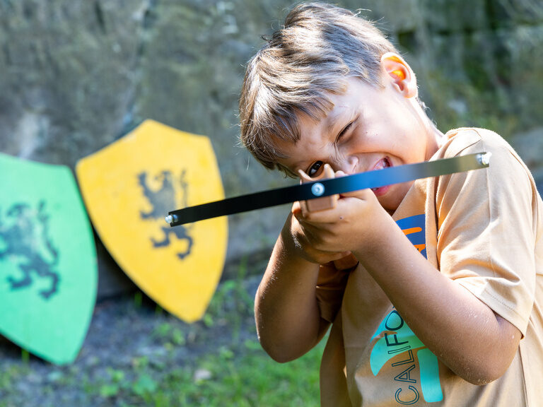 Kind mit Pfeil und Bogen beim Spielen in der Natur beim Family Club Harz