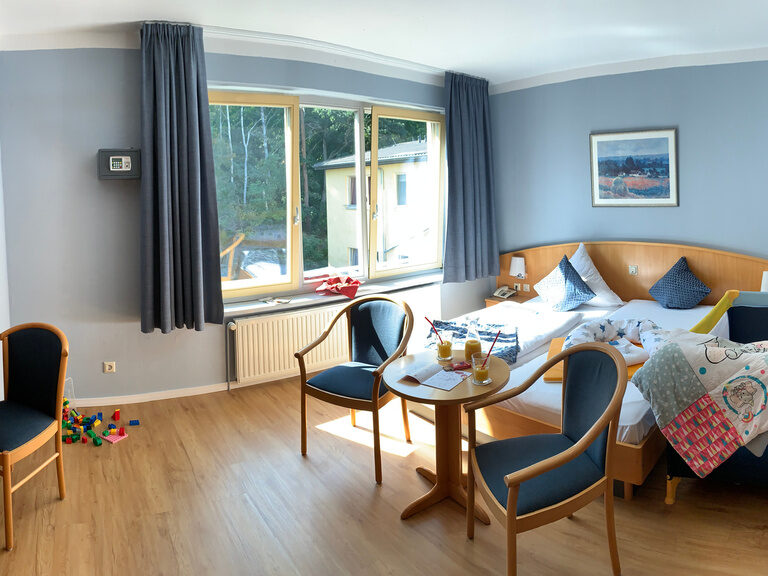 Doppelzimmer mit Bett und Sitzecke in Holzoptik