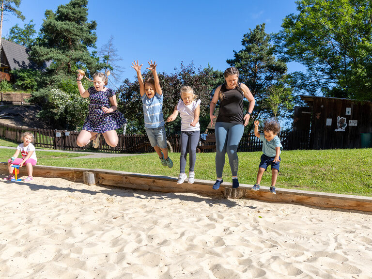Familie hüpft gemeinsam in einem Sandkasten