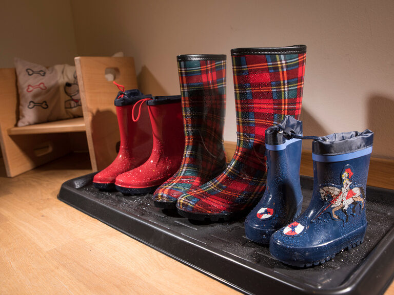 3 Paar Gummistiefel auf einer Schuhablage