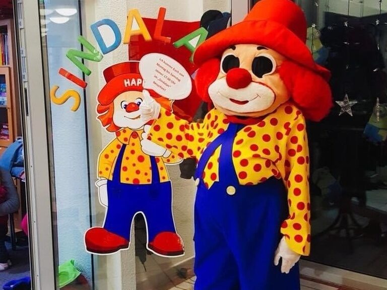 Familotel Maskottchen Happy vor Glastür des Happy Clubs