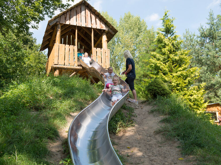 Holzhäuschen mit Rutsche und Kindern