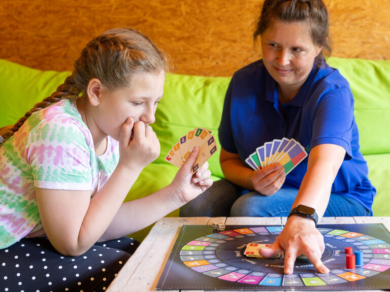 Kind spielt mit einer Betreuerin ein Brettspiel im Family Club Harz
