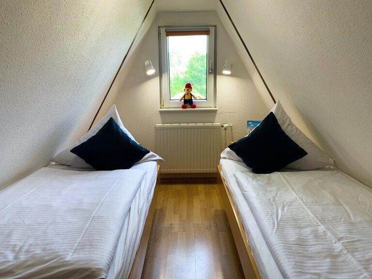 Helles Kinderzimmer mit Einzelbetten unter Dachschräge