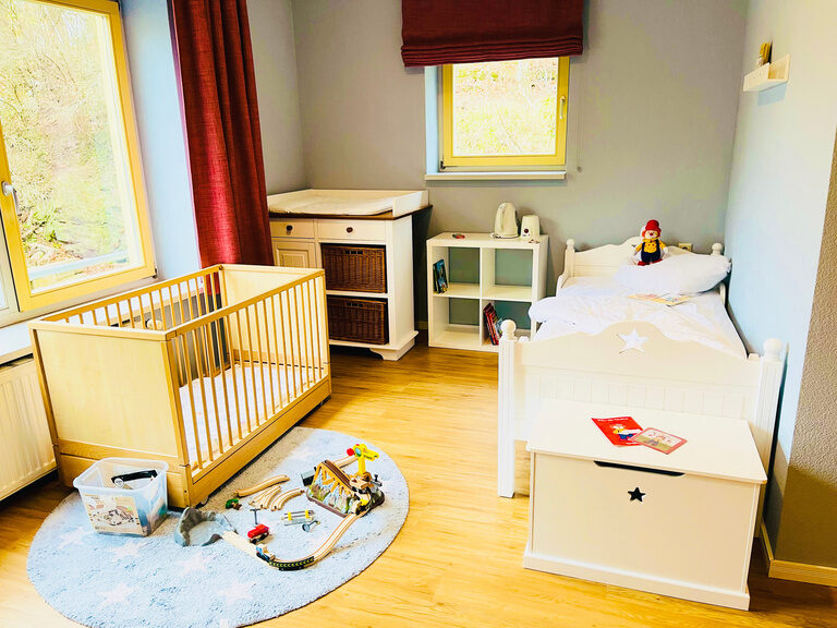 Helles Kinderzimmer mit Einzelbett und Gitterbett und Spielzeug