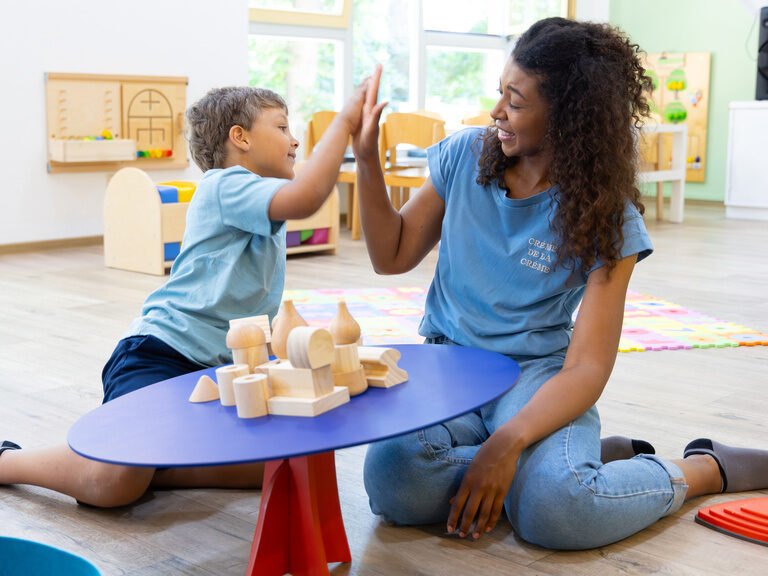 Mutter und Kind klatschen sich im Spielzimmer in die Hände