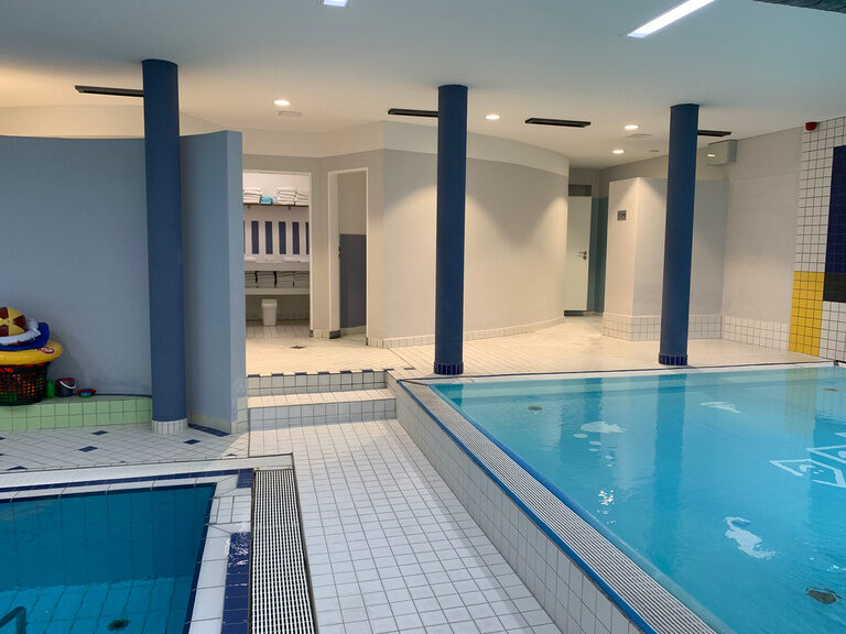 Schwimmbad mit weißen Fliesen und blauen Säulen