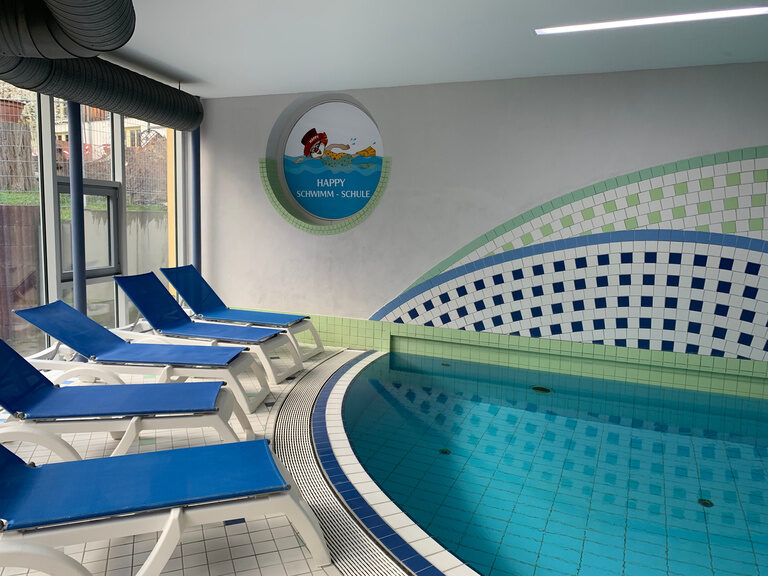 Schwimmbecken und blaue Liegestühle