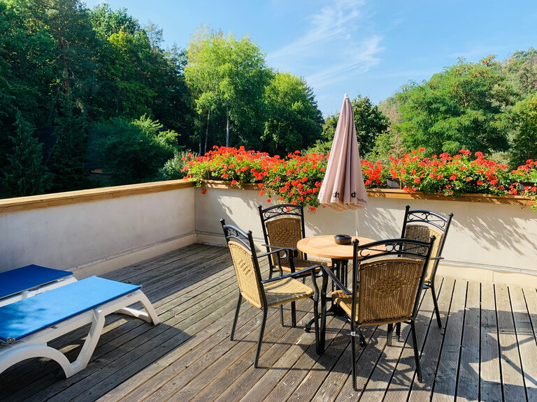 Sonnige Terrasse mit Liegestühlen und Sonnenschirm