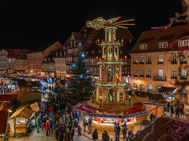 Weihnachtsmarkt im Dunkeln Weihnachtspyramide auf dem Weihnachtsmarkt neben einer Tanna