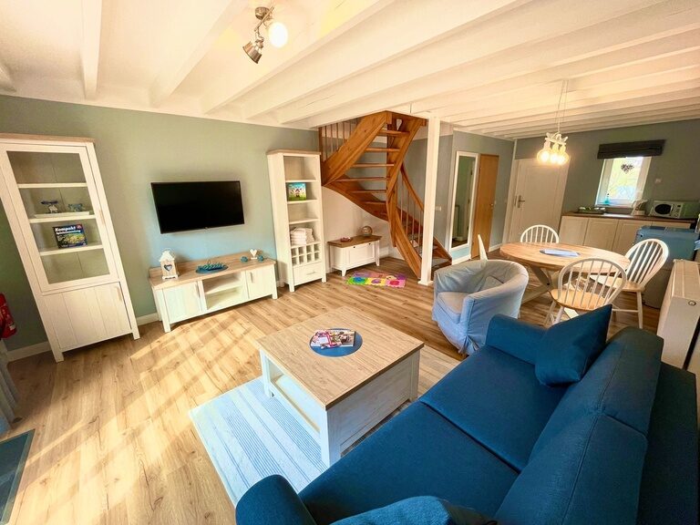 Wohnbereich mit Fernseher, Bücherregal und blauem Sofa in einer Unterkunft im Family Club Harz.
